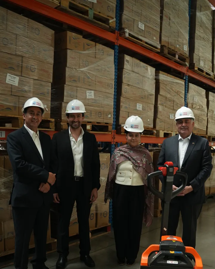 Equipo de Marea Alta con casco en la bodega, frente a pallets de productos Tres Osos.